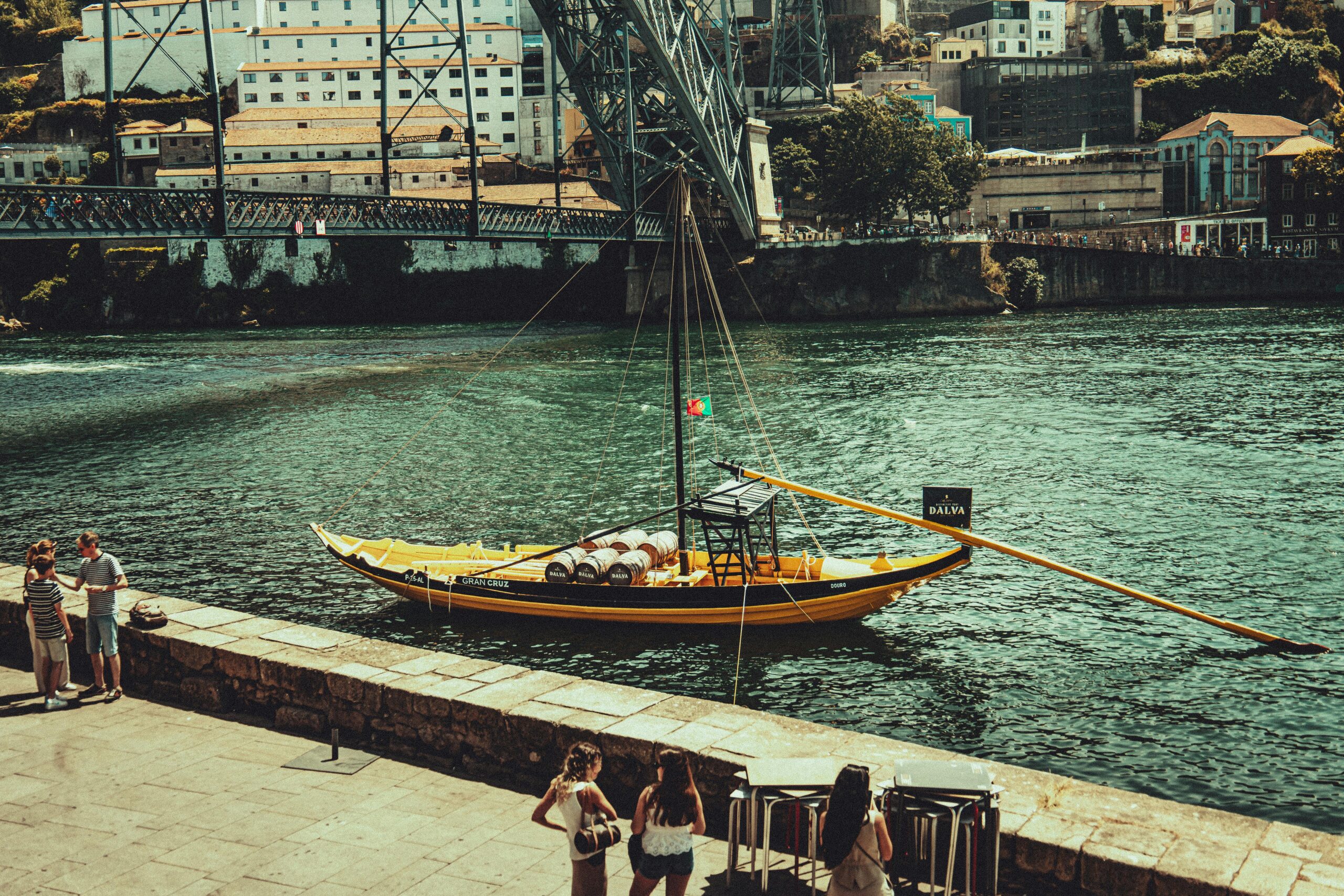 A Brief (and Delicious) History of Porto Scenic view of a Rabelo boat on the Douro River with Porto city in the background.